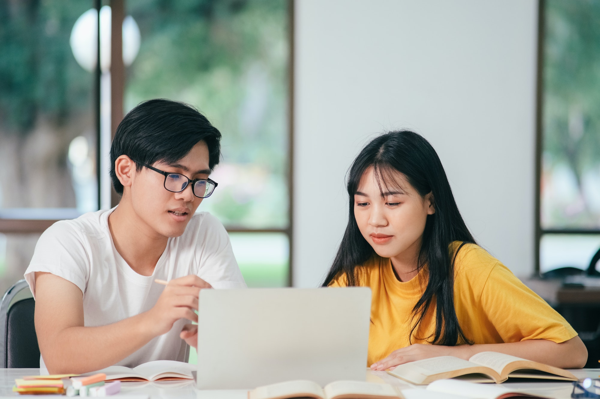 Young asian students campus helps friend catching up and learning.